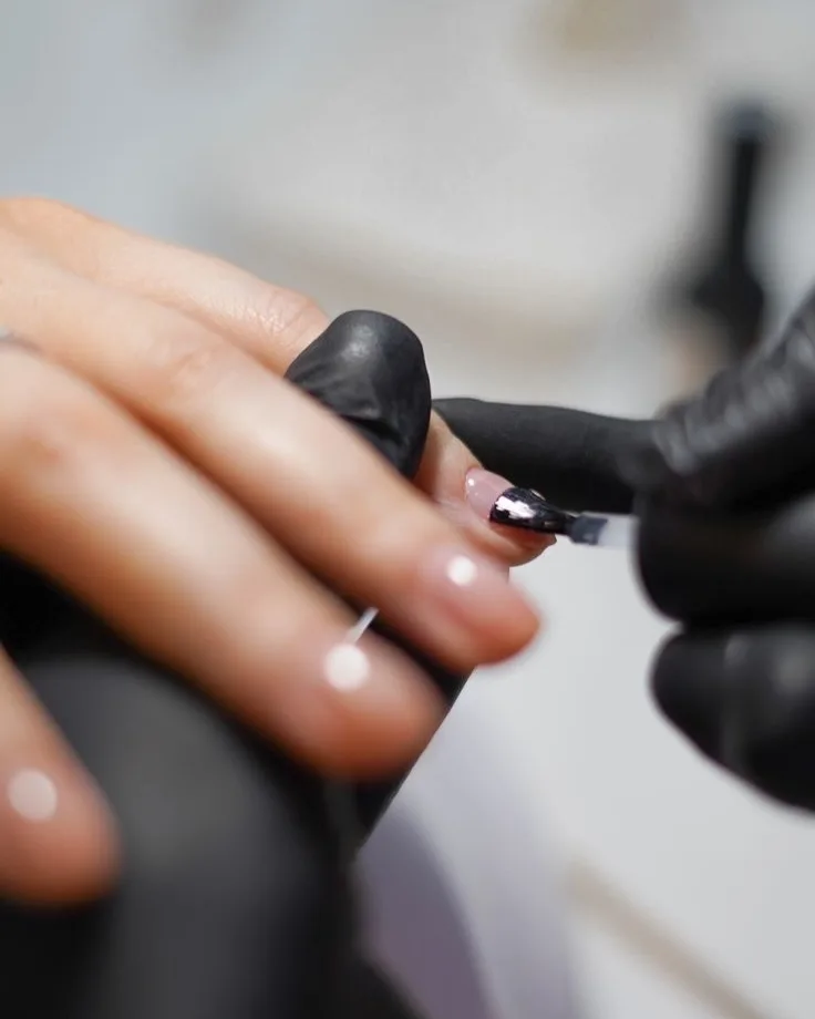 Esmalte sendo aplicado com luva preta, de perto