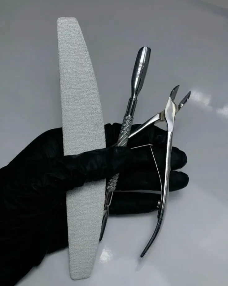Lixa, espátula e alicate esterilizados na mão enluvada