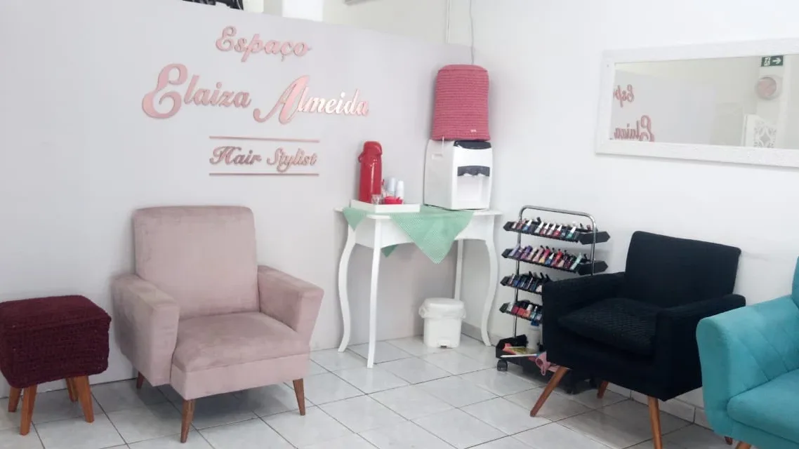 A parede com o nome da casa, as poltronas de espera e a água